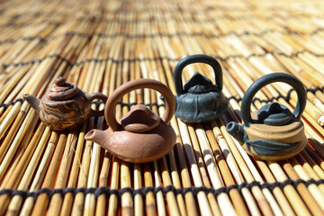 Miniature teapots on a bamboo mat in the sun