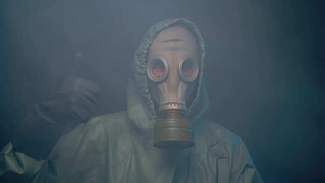 Man in gas mask and protective suit in the smoke