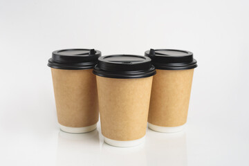 Three eco friendly paper craft cups for coffee to go with black lid on the white background. Zero waste, plastic free concept. Sustainable lifestyle. Composition with front view.