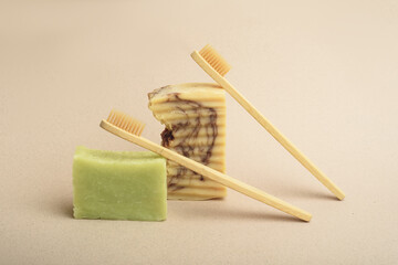 Two bamboo toothbrushes and two sets of handmade soap on the beige background. Natural hygiene products. Zero waste concept.