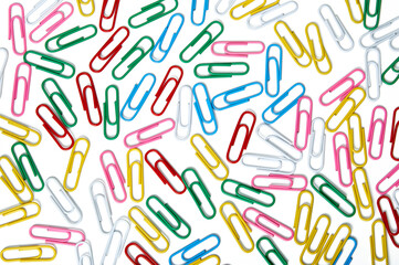 A lot of multi-colored colored paper clips on a white background.