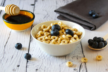 Honey rings with blueberries in a bowl on the table wooden background. Breakfast. Flat lay. Horizontal orientation.