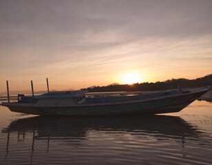 Wooden fishing boat at sunrise.