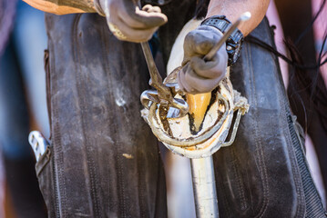 Horse farrier at work - trims and shapes a horse's hooves using farriers pincers, rasper and knife....