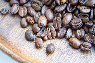 Artistic composition in natural light. Coffee beans close up, on a dark wood plate