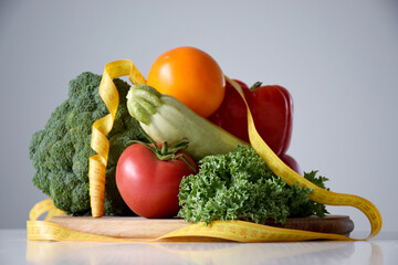 Assortment of fresh organic vegetables and measuring tape on wooden cutting board. Balanced nutrition, healthy eating, weight loss, detox or dieting concept.