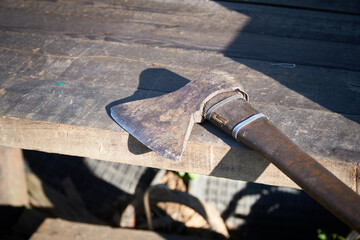 An old ax with a damaged blade lies on a wooden table