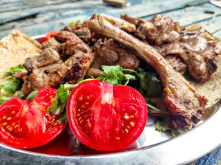 Grilled lamb loin with tomatoes and herbs is on a platter