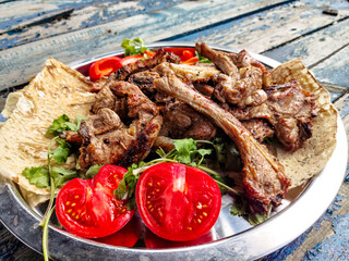 Grilled lamb loin with tomatoes and herbs is on a platter