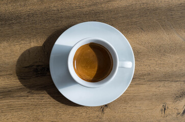 Simple top-down shot of a white cup of double espresso.
