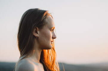 Side view close up headshot of a young caucasian woman looking at sunset