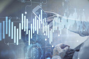 Double exposure of man's hands holding and using a digital device and forex graph drawing. Financial market concept.