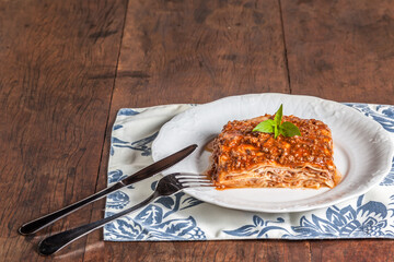 A slice of lasagna on a wood table