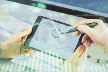 Double exposure of man's hands holding and using a phone and financial chart drawing. Market...