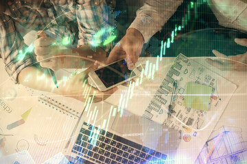Double exposure of forex graph drawing and man and woman working together holding and using a mobile device. Trade concept.