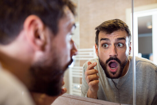 Beard man applying hydrating cream on face in bathroom