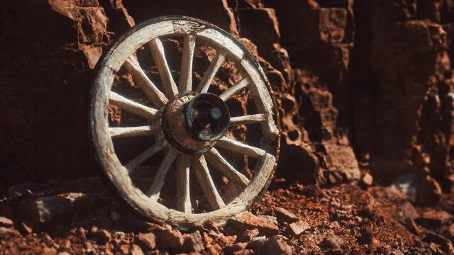 old wooden cart wheel on stone rocks