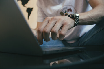 close-up of male hands typing text message on laptop keyboard,  young male freelancer working from home 