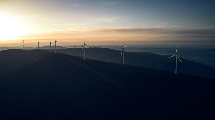 Aerial view of sunset over mountains and wind turbines