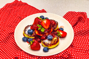 Cottage cheese pancakes with fresh berries and strawberry sauce. Healthy breakfast concept on stone background