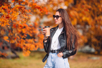 Fall concept - beautiful woman in autumn park under fall foliage