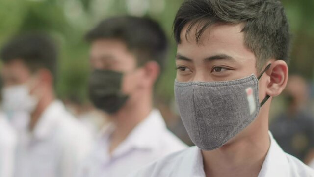 Slow motion of male Asian high school students in white uniform on the semester start wearing masks and stand in line in the morning  during the Coronavirus 2019 (Covid-19) epidemic.
