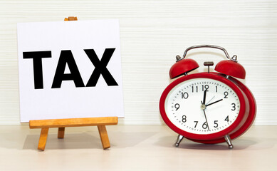 Wooden blocks with the word TAX on calculator and money. Tax planning, tax refund or Tax concept.