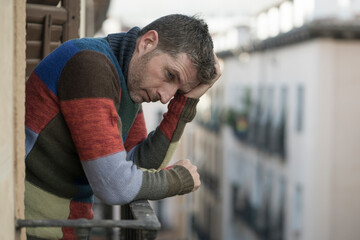 urban lifestyle emotional portrait of 30s handsome man sad and depressed at home balcony leaning upset feeling desperate suffering depression problem looking to city street