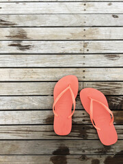 orange jandals or flip-flops on a wooden boardwalk near a swimming pool, top-down minimal detail photo