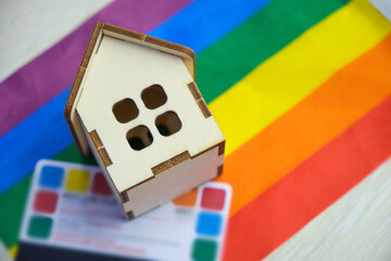 credit card and a small wooden house on the flag of the lgbt community, purchase of suburban real estate by same-sex couples