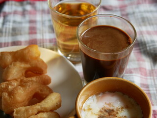 set of moring thai hot drink, coffee with deep-fried dough stick and soft boiled eggs, local thai food and drink.