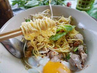 Local thai noodle roll on shopstick with soft boiled eggs, vegetable and meat ball in soup bowl  