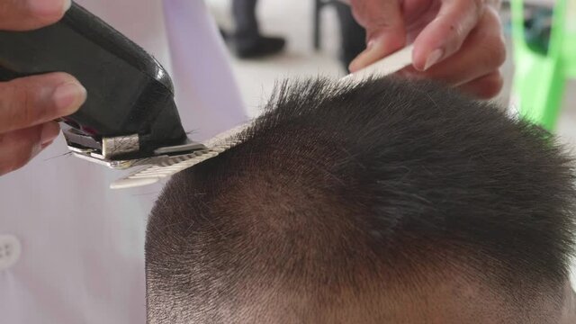 Slow motion of short haircuts for elementary school male students and male high school students in Thailand by using a hair clipper to cut hair with a comb in barber shop.