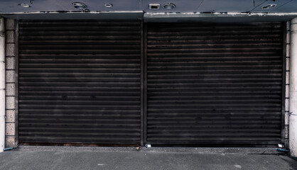 Dark gray weathered corrugated metallic roll up doors. Concept of closed, shuttered or bankrupt establishment or business background.