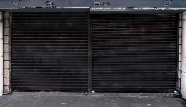 Dark gray weathered corrugated metallic roll up doors. Concept of closed, shuttered or bankrupt establishment or business background.