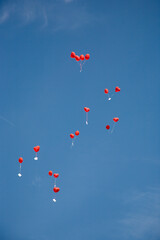rote Herzluftballons vor blauem Himmel