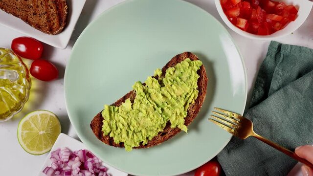 Top view of healthy and vegan avocado toast in a green plate on white background