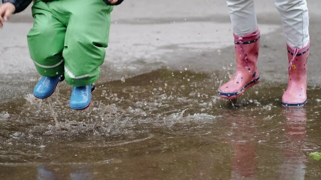 Family in a rainy park. Kids in a puddle. Child having fun outdoors.