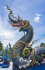 Fototapeta na wymiar Chiangrai, Thailand - June 7, 2020: Blue Serpent or Naga on Blue Sky Background with Natural Light in Wat Rong Suea Ten Temple at Chiangrai Thailand in Portrait View