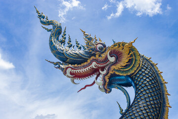 Fototapeta na wymiar Chiangrai, Thailand - June 7, 2020: Blue Serpent or Naga on Blue Sky Background with Natural Light in Wat Rong Suea Ten Temple at Chiangrai Thailand in Zoom View