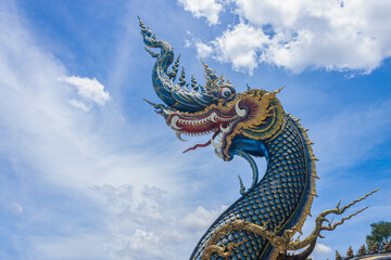 Fototapeta na wymiar Chiangrai, Thailand - June 7, 2020: Blue Serpent or Naga on Blue Sky Background with Natural Light in Wat Rong Suea Ten Temple at Chiangrai Thailand