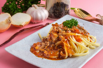 Delicious spaghetti with bolognese sauce served on a white square plate