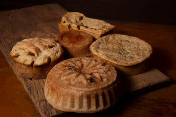 artisan breads on a wooden table dirty with flour and with ingredients olives, eggs and sausage and rosemary.