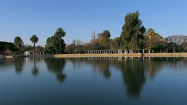 Trees and Palm trees reflected in a mirror of water at the park Parque General San Martin, in Mendoza, Argentina.