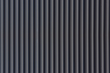 A corrugated fence of  grey metal sheets. Texture of metal fence picket Profile decking. Internal primed side of a metal picket fence. Profiled metal.