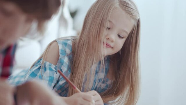 Adorable preschool brother and sister kids playing and drawing together. Beautiful cute girl with blonde hair painting picture with pencils. Carefree childhood concept.