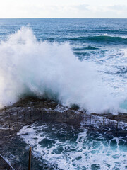 Wave crashing into the edge of rock pool.