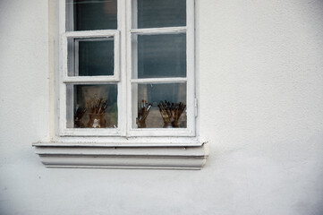 Białe okno za stojącymi na parapecie pojemnikami z pędzlami