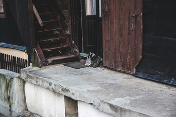 Dwie pary butów wystawione na ganek obok schodów - obrazy, fototapety, plakaty