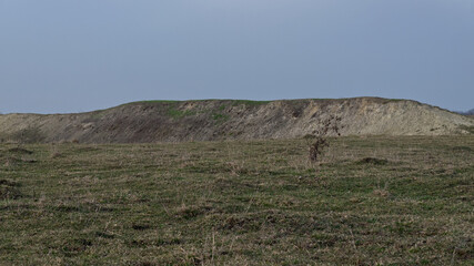 Slope of a small clay hill in a field in spring. Landscape.